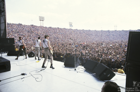 (L-R) Paul Simonon, Joe Strummer and Mick Jones of The Clash on stage at JFK Stadium in Philadelphia, PA. September 25, 1982. Image #: Clash982_1982_12 © Bob Gruen Paul Simonon, Joe Strummer and Mick Jones, Philadelphia - 1982