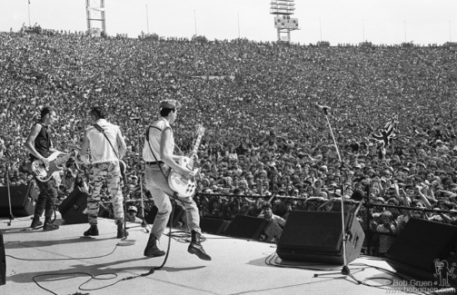 (L-R) Paul Simonon, Joe Strummer and Mick Jones of the Clash on stage at JFK Stadium in Philadelphia, PA. September 25, 1982. Image #: Clash982_6-18_1982 © Bob Gruen Paul Simonon, Joe Strummer and Mick Jones, Philadelphia - 1982